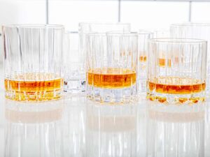 An old fashioned glass holding amber whiskey and a large ice cube